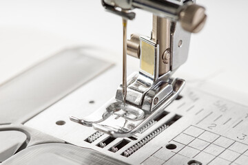 Modern white sewing machine presser foot closeup, macro. Sewing equipment, work tool for atelier business, manufacturing, occupation.