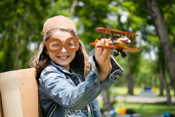 A little girl on vacation at the park with a pilot outfit and flying equipment. Run around and have fun with her dreams.