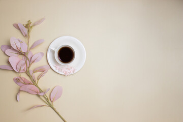 A cup of coffee with flowers over the light background with copy space.