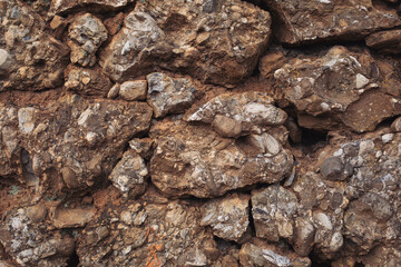 Close up shot of a beautifully textured dry stone wall. Old, rough, gray stone wall background texture. Masonry texture of natural gray stone. Dark stones and rocks of different shape.