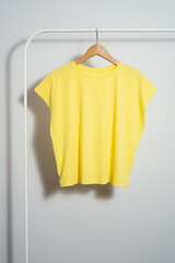 Yellow t-shirt mockup on wooden hanger hanging on a clothes rack