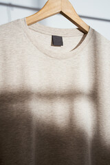 Close up shot of round neckline beige t-shirt mockup on wooden hanger