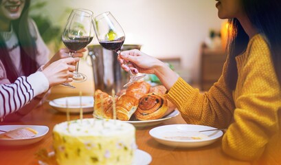 Obraz premium Cheerful friends enjoying home Birthday holiday party. Asian Friends cheering drinking red wine celebrating New Year party.