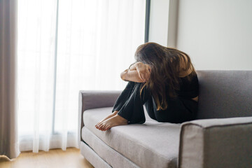 Sad woman thinking about problems sitting on a sofa upset girl feeling lonely and sad from bad relationship or Depressed woman disorder mental health.