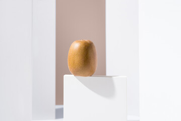 Kiwi dorado sobre un soporte blanco y fondo marrón