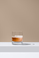 Vaso de whisky con hielo sobre un fondo marrón