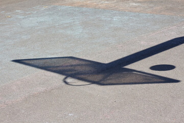 The shadow of a basketball backboard on a yard sports ground