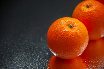Close up shot of fresh oranges standing side by side on light on black background with free space
