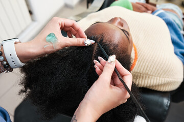Close-up of a hairdresser's hands doing an afro woman's hair