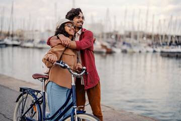 A romantic tourists with bike are hugging on the pier and enjoying the view.