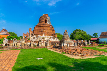 Fototapeta na wymiar Ruined pagoda with surrounded by lion sculptures in Wat Thammikarat Ayutthaya, Thailand