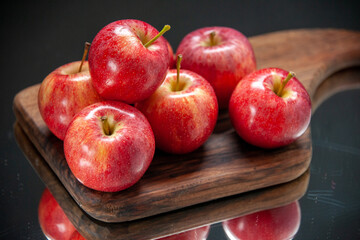 Top view of fresh red apples on wooden cutting board on dark color background