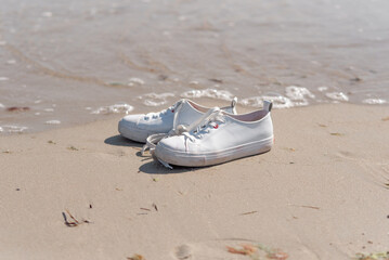Fototapeta na wymiar White boots stand on the beach of the sea. Close-up