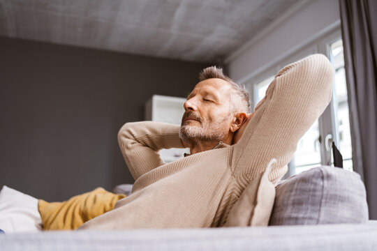 Older Man Leaning Relaxingly on His Sofa with Closed Eyes, Gazing Upwards