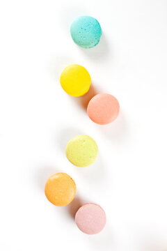 Scattered colorful macarons shot from top angle on white background