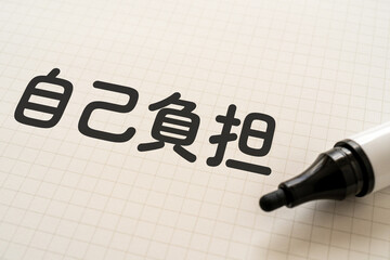 自己負担と書かれたノートとマーカー