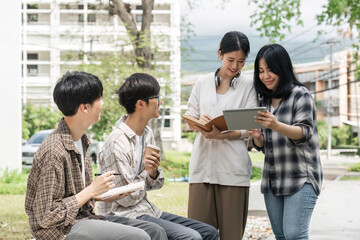 University students sitting together at table with books and laptop and tablet. Happy young people doing group study in university
