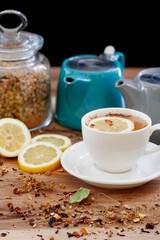 Herbal tea in a cup and teapots with lemon slices