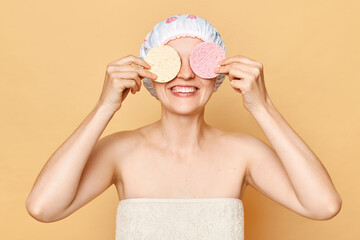 Face cleansing. Cheerful attractive young woman covering eyes with soft celluloses sponges, washing...