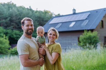 Happy family near their house with solar panels. Alternative energy, saving resources and...