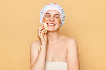 Face cleansing. Beauty treatment. Smiling attractive naked young woman holding soft yellow facial...