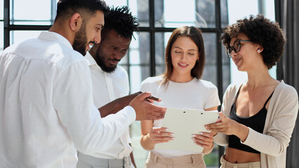 Employees working at computer together, discussing content
