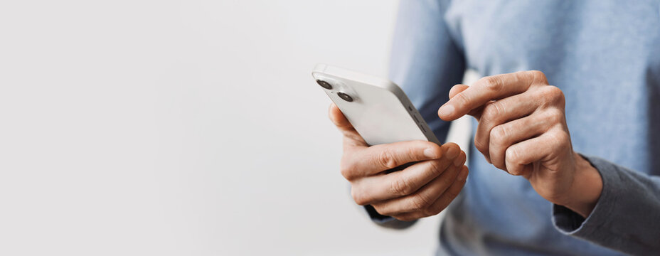 Closeup Of Adult Male Hand Using Mobile Phone, Young Man Texting On Smartphone Over Grey Background, Panoramic Banner With Copyspace