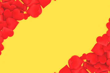 Frame made of red hearts confetti on a yellow background. Place for text.