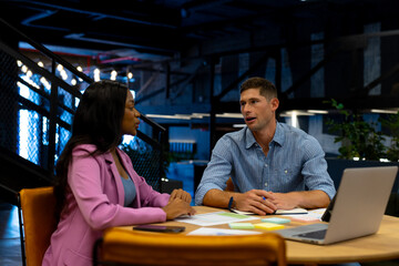 Diverse male and female colleagues in discussion using laptop in casual office meeting