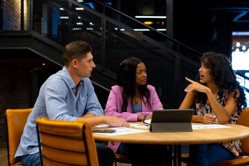 Diverse male and female colleagues in discussion using tablet in casual office meeting