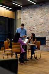 Diverse male and female colleagues in discussion using tablet at casual office meeting
