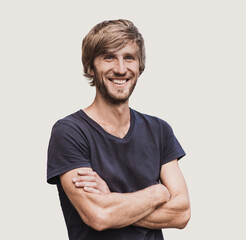 Obraz premium Portrait of handsome smiling young man with folded arms. Smiling joyful cheerful men with crossed hands studio shot. Isolated on gray background