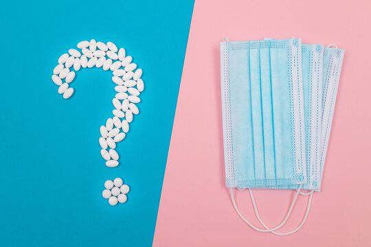 Question Mark Made from White Pills and Tablets with Medical Face Masks, Lying on Split Blue and Pink Background. Global Pharmaceutical Industry and Medicinal Products