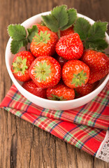 bowl with fresh strawberries on rustic table on wooden background