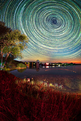 The movement of stars on a long exposure over the waters of the reservoir