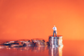 Miniature people, businessman standing on stack coins using as business and financial concept
