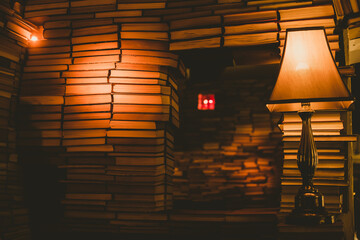 Old-fashioned lamp illuminating walls made of books - 615098193