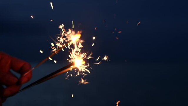 Hand holding sparklers fireworks celebration fourth of July, USA Independence Day July 4th on outdoor sunset background. Concept 4th of July, Holiday, USA, Freedom, Juneteenth, Memorial, Veterans, Day