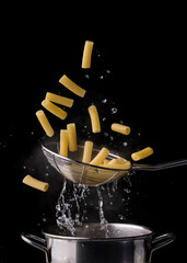 Wholemeal fusilli, steaming Italian pasta floating and dripping ready to season on a black background.