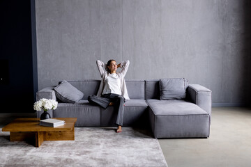 Happy woman relaxing on comfortable soft sofa enjoying stress free weekend at home