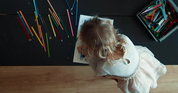 Overhead shot of toddler girl draw with color pencil at home