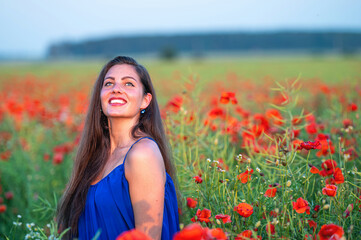Naklejka na ściany i meble portrait of elegant young woman in poppy field in evening sunlight