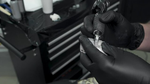 Tattoo artist working with tattoo machine and ink, needles, close up