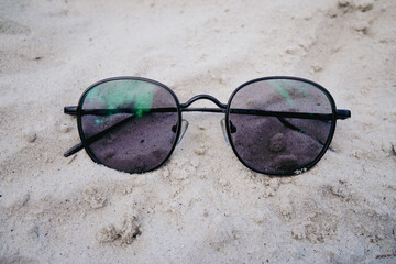 Closeup of protective sunglasses on a sandy beach on a tropical beach. Summer vacation concept.