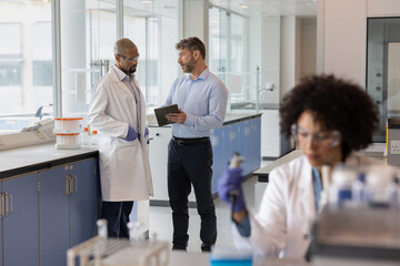 Scientists discussing data using a digital tablet in a laboratory