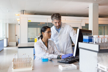 Female science student learning how to anaylse data on a computer in a laboratory