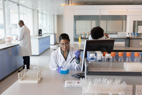 Female scientist pipetting in a busy laboratory 