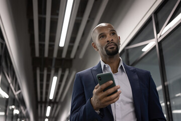Businessman leaving office late at night holding smartphone