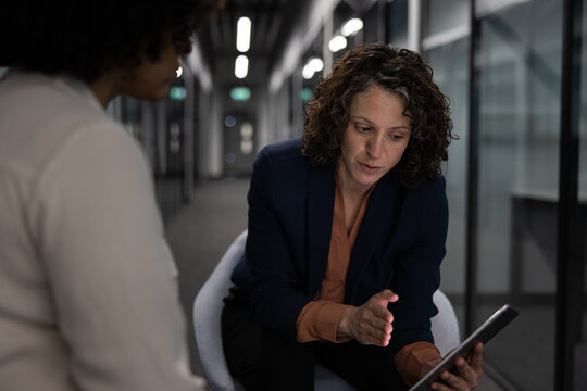 Businesswoman in a meeting with a coworker working late in the office using a digital tablet - Powered by Adobe