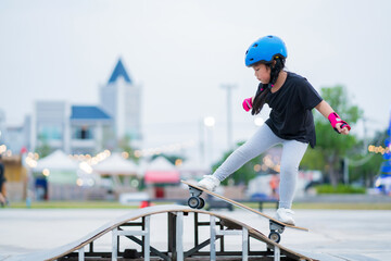 Child or kid girl playing surfskate or skateboard in skating rink or sports park at parking to wearing safety helmet elbow pads wrist and knee support © CasanoWa Stutio